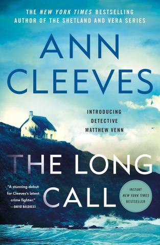 A white lone house on a hill leading to a turbulent shoreline, in the foreground in dark blue lettering says Ann Cleeves, and in white lettering there is the title The Long Call. The whole cover has a blue tint.