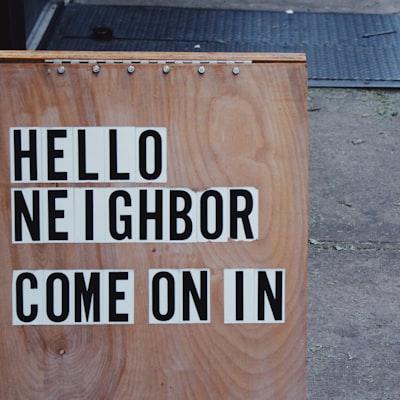 sign on wood with "Hey Neighbor come on in" written on it