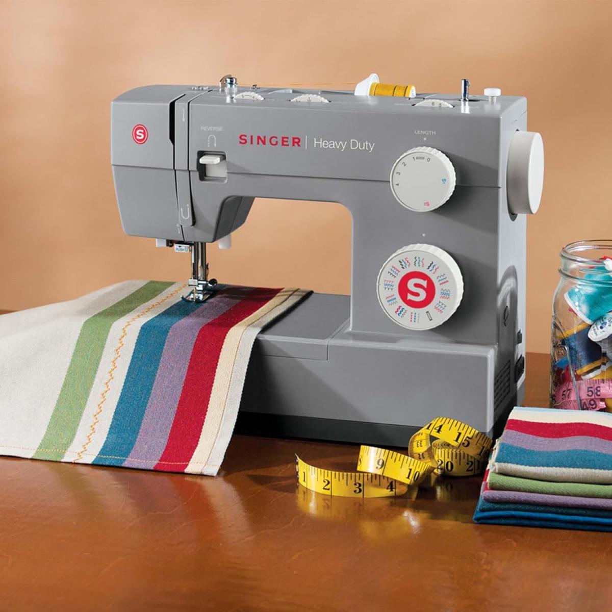 A Singer Sewing Machine with fabric, a tape measure, and other sewing tools