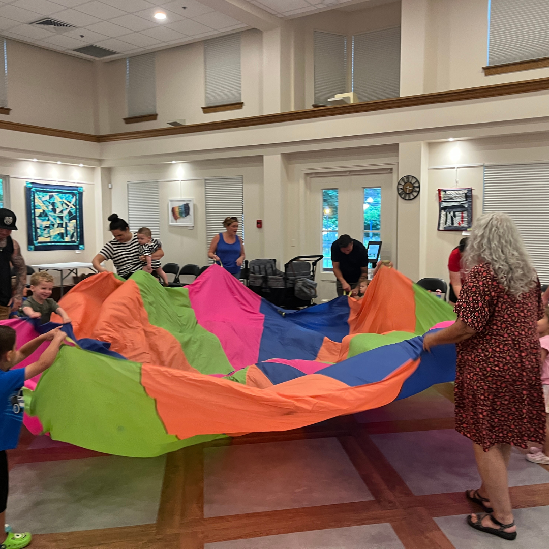 Ms. Lori and program attendees dancing with parachute.